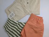 trois shorts et un t-shirt posés sur une surface blanche