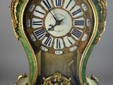 a green and gold clock with roman numerals on it