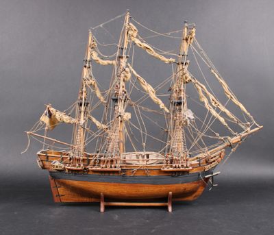 wooden model of a sailing ship on a stand on a gray background