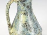 a blue and green vase with a handle on a white surface