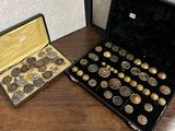 un coffret noir contenant des pièces d'or et d'argent, posé sur une table