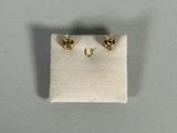 a close up of a pair of gold earrings on a white cloth
