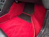 the interior of a sports car with red carpeting and black leather