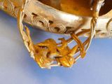 a silver vase with a gold decoration on it