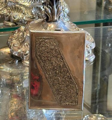 a glass table with a silver vase and a mirror on it