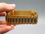 a person holding a gold bracelet in their hand