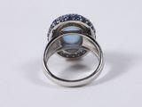 an image of a ring with a blue stone surrounded by blue sapphires