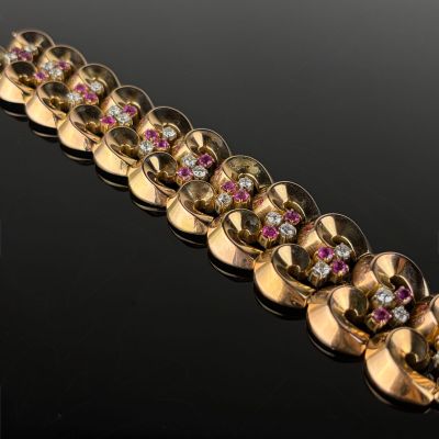 a close up of a gold bracelet with pink and white stones