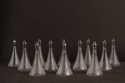 six clear glass cones are lined up against a black background