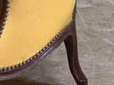 yellow and brown upholstered chair with beaded trim and wood legs