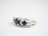 a close up of a diamond and sapphire ring on a white surface