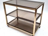 a close up of a glass and brass coffee table on wheels