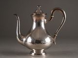a silver tea pot with a handle on a table