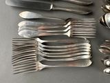 many spoons and forks laid out on a table