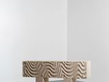 un banc en bois posé sur un sol en béton, près d'un mur blanc