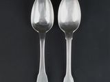 two silver spoons on a black surface with a black background