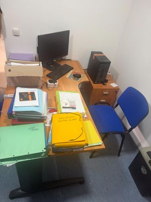 un bureau sur lequel se trouvent un ordinateur, un écran et plusieurs dossiers