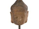statue représentant une tête de Bouddha posée sur un socle, sur fond blanc