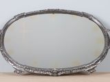 silver plated oval mirror with handles on a wooden table