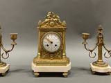 three candles and a clock sitting on a table