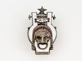 an image of a silver broochle with a face and a star on it