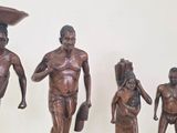 five figurines of a man carrying a basket on his head
