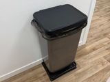 une poubelle noire posée à côté des toilettes dans une salle de bains