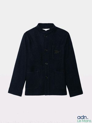 La veste est noire et se ferme à l'aide de boutons.