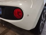 the rear end of a white sports car parked in a garage
