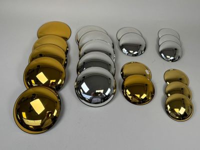 une multitude de boutons dorés et argentés brillants posés sur une table blanche