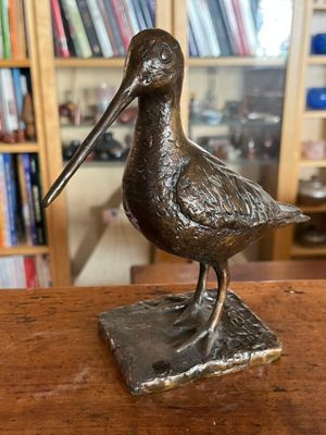 une statue représentant un oiseau perché sur une table en bois