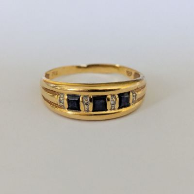 gros plan d'une bague en or avec des pierres noires et blanches