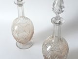 two clear glass bottles sitting next to each other on a white surface