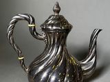 an antique silver tea pot on a grey background