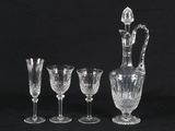 four crystal wine glasses and a decanter on a black background