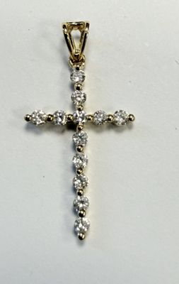 un gros plan d'un pendentif en forme de croix en diamant posé sur une surface blanche