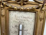 a gold frame with a thermometer on it