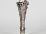 un vase ancien en argent posé sur un socle, sur fond blanc
