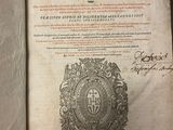 an old book with a picture of a coat of arms on top of it
