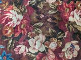 a cat that is laying on a bed with a floral blanket