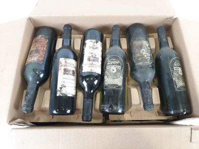 Plusieurs bouteilles de vin se trouvent dans une boîte en carton posée sur une surface blanche.