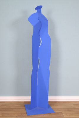 sculpture bleue représentant une femme debout sur un plancher en bois, devant un mur bleu