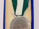 silver medal with green and white ribbon in a blue box