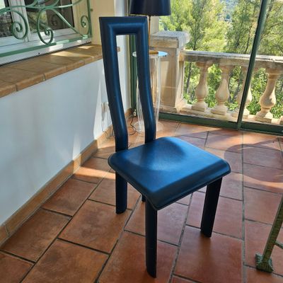 une chaise bleue posée sur un sol carrelé devant une fenêtre