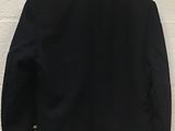 the back of a black jacket hanging on a white wall