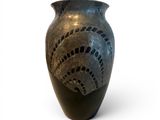 a black vase with holes in it on a white surface
