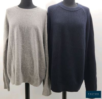 two sweaters on a mannequin stand in front of a white wall