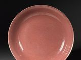 an image of a pink plate on a stand against a black background