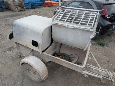 a small cement mixer on a trailer in a parking lot