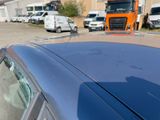 a blue car parked in a parking lot next to a truck